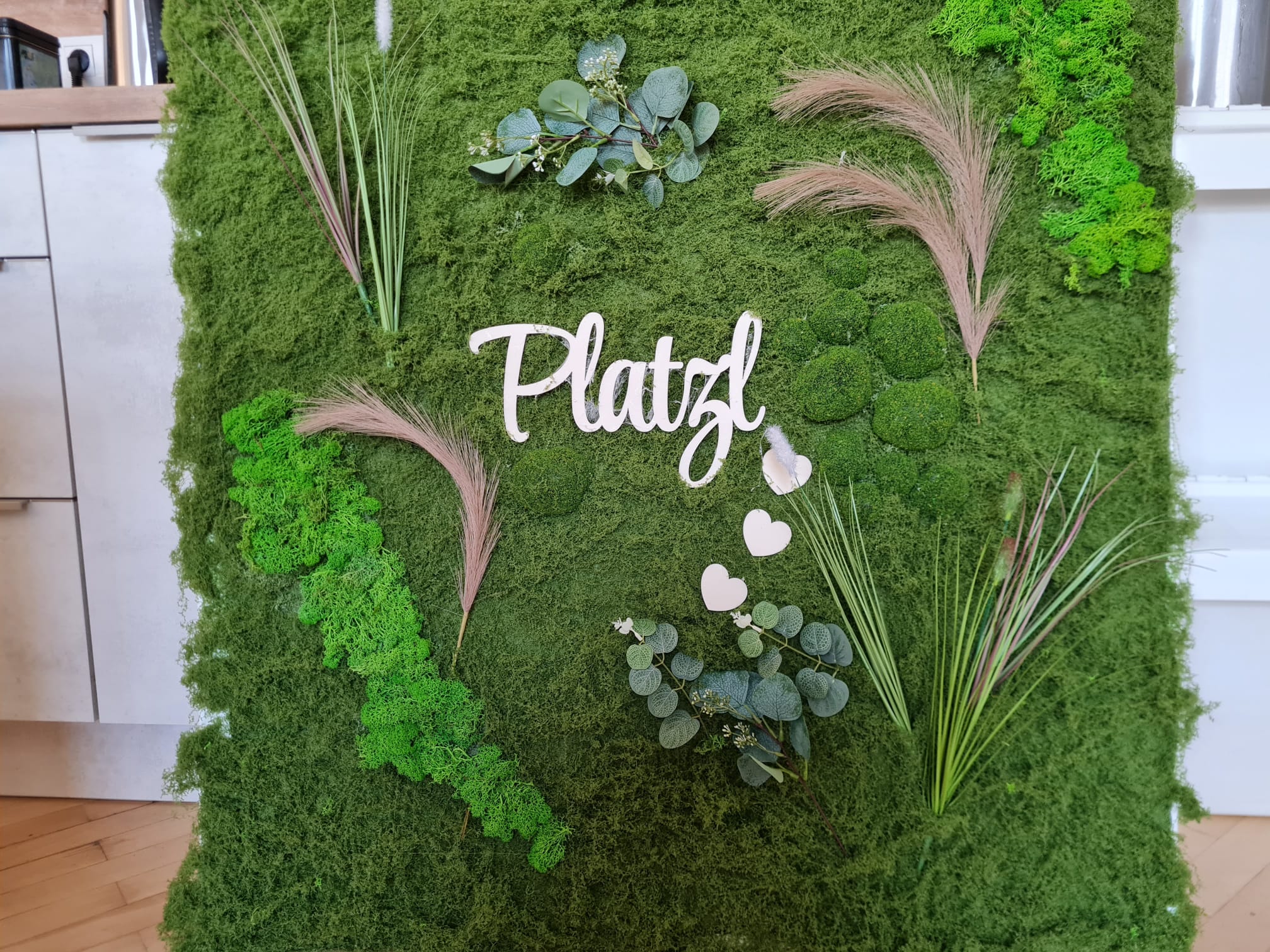 Liebevoll gestaltete Mooswand mit dem Schriftzug Platzl